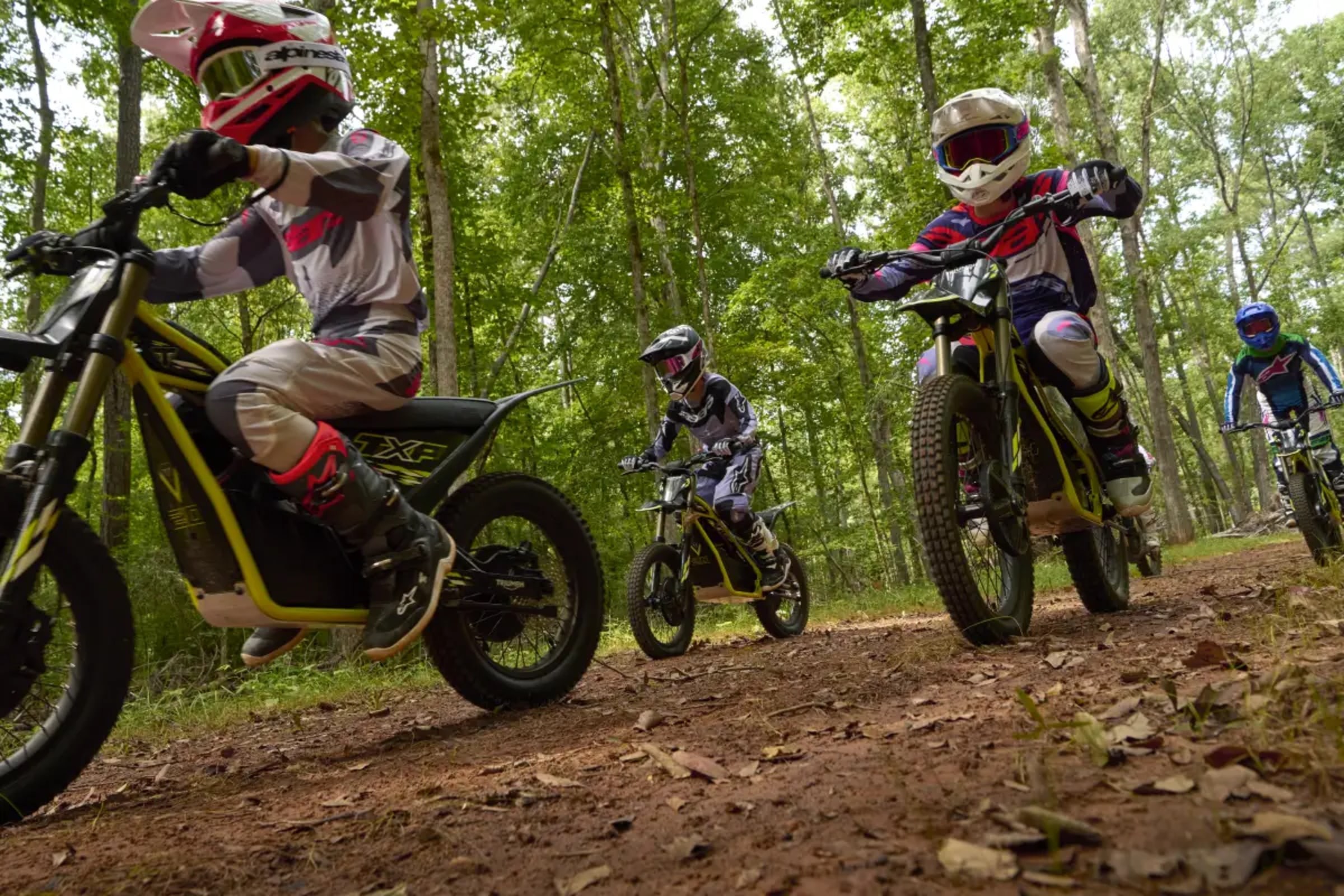 Youth riders on Triumph TXP electric bikes on forest trail