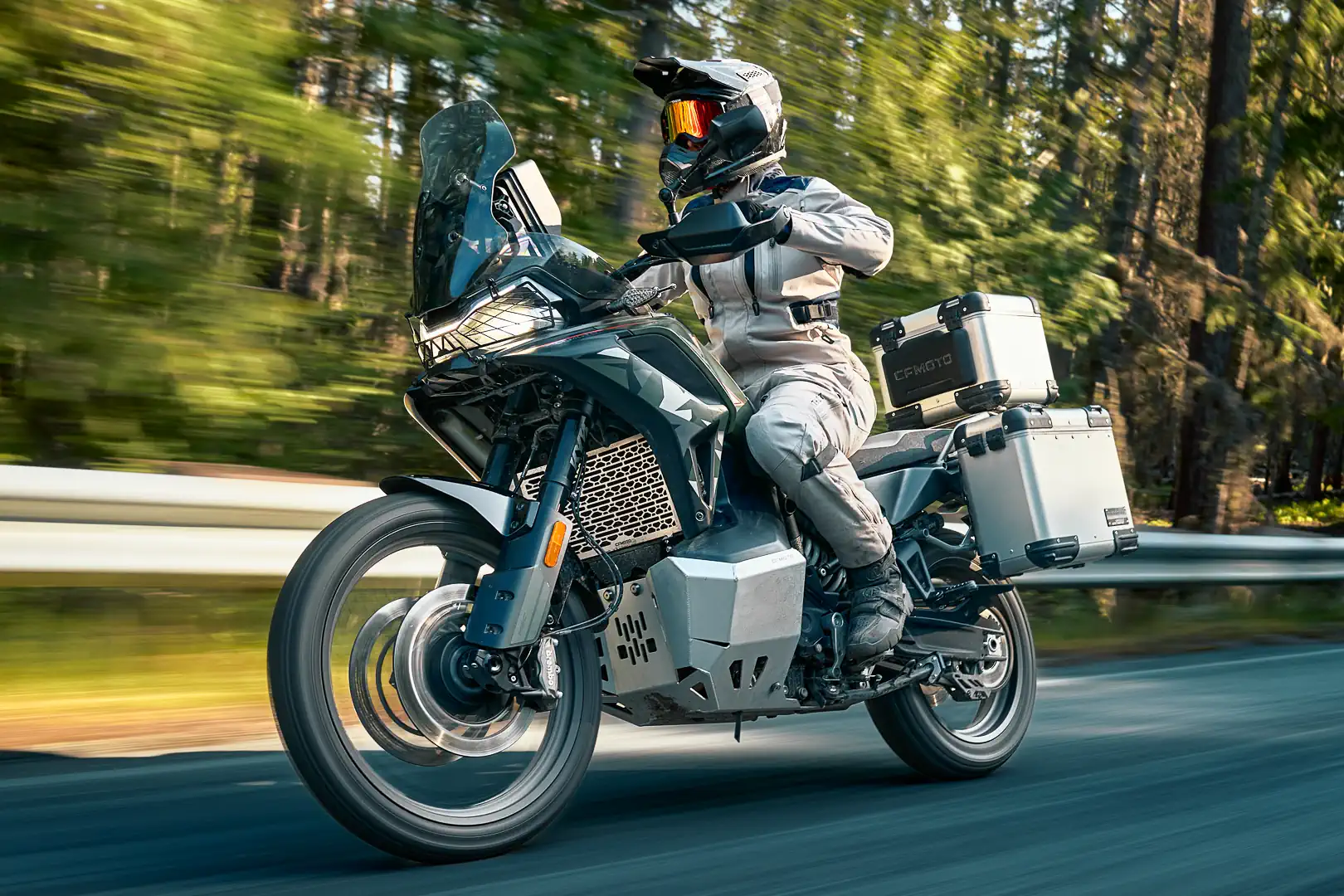2027 CFMoto Ibex 950 action — rider on pavement with CFMoto aluminum luggage, 21-inch front