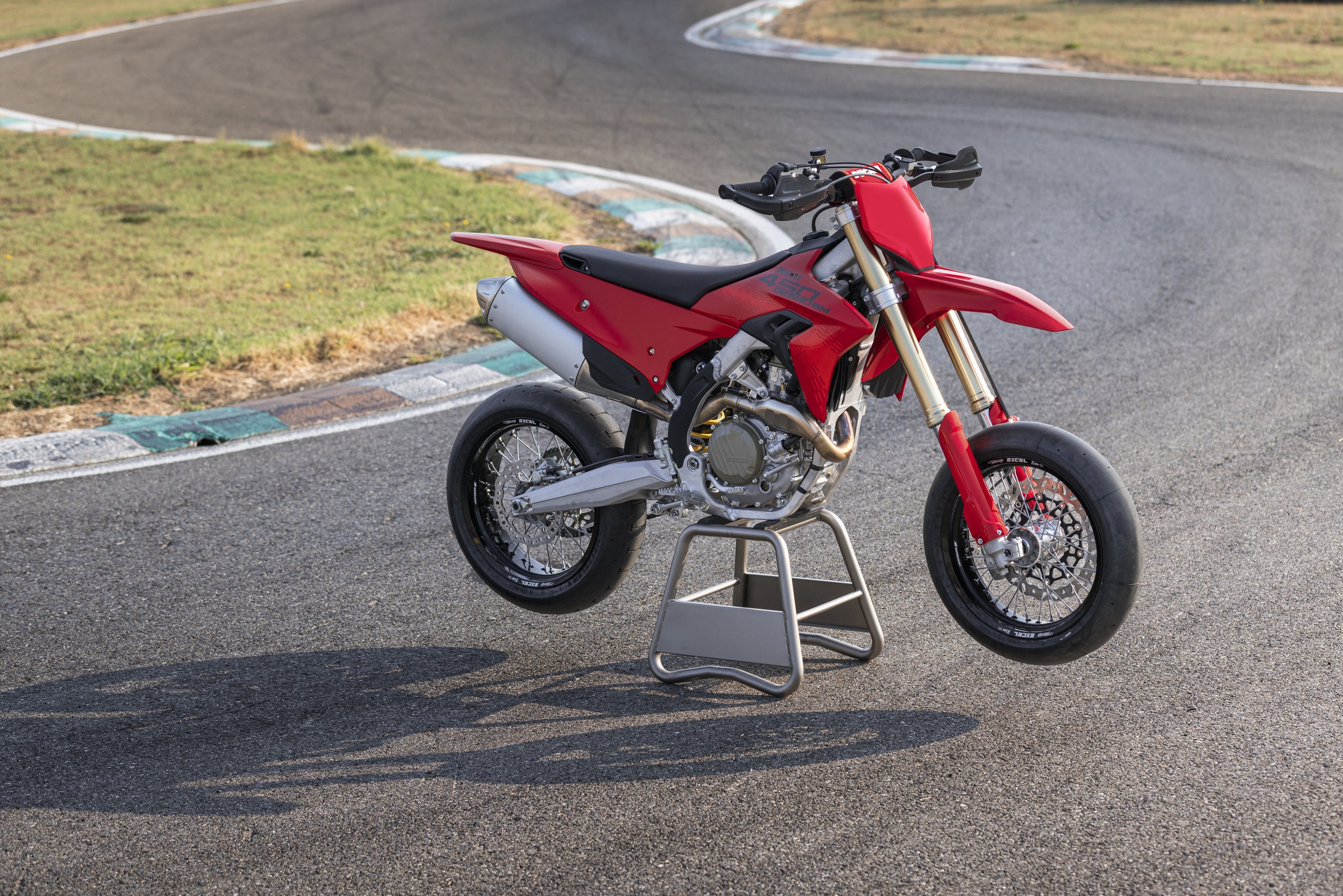 2027 Ducati Desmo450 SM red racing supermoto on paddock stand — Excel BarTubeless rims, Metzeler Racetec SM slicks, Showa USD fork