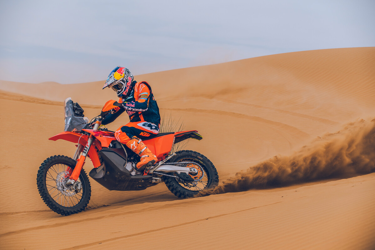 2027 KTM 450 Rally Replica carving a sand dune with large roost plume
