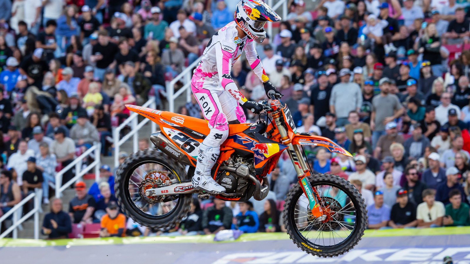 Jorge Prado in pink and white Fox gear with Red Bull logos jumps his number 26 KTM in front of a packed grandstand at Rice-Eccles Stadium in Salt Lake City