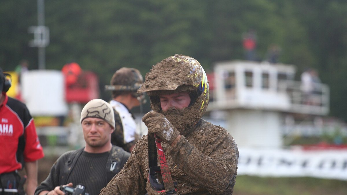 Mud-caked motocross rider adjusting goggles in the pits at the 2012 Motocross Nationals, Nanaimo