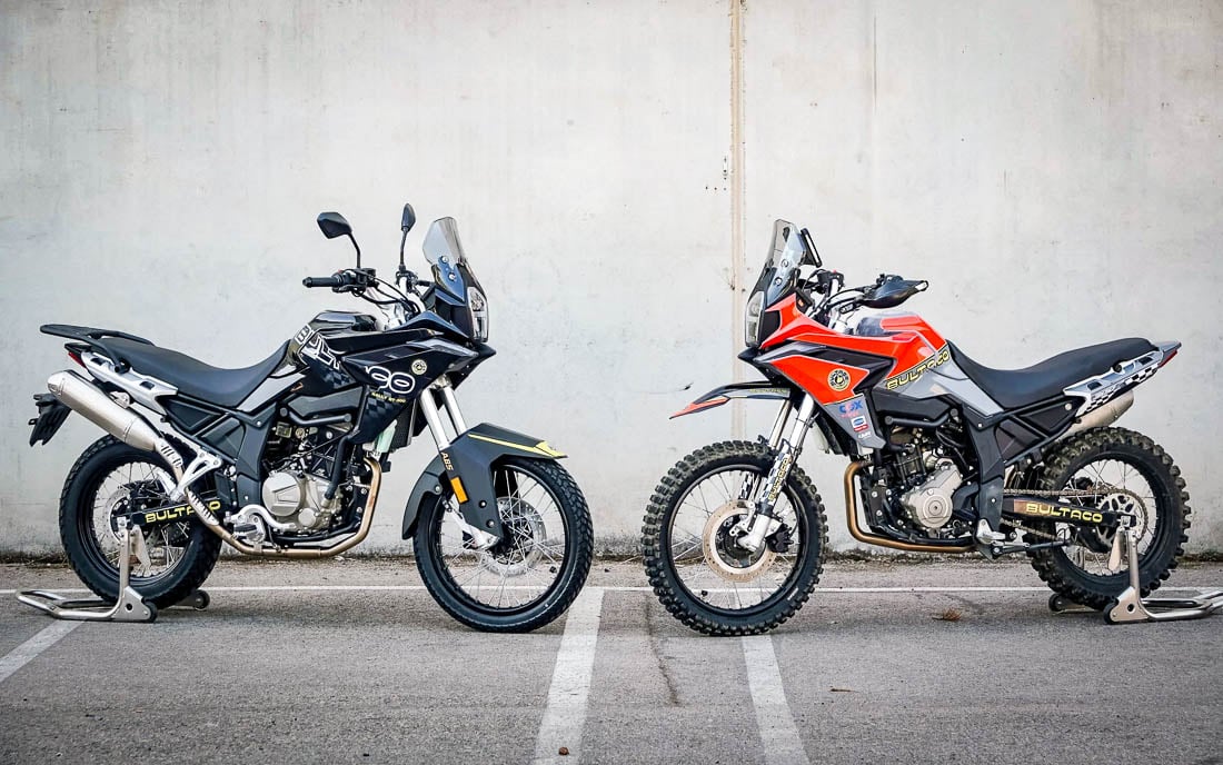 Two Bultaco Rally GT 300 bikes side-by-side — black street dual-sport and orange knobby rally trim