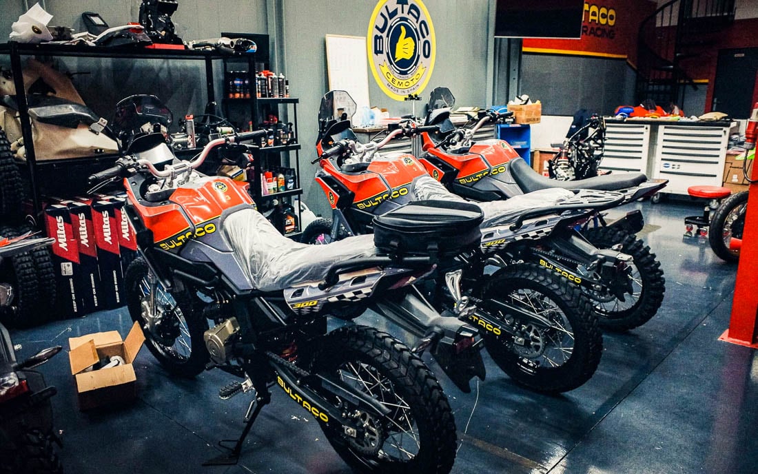Three Bultaco Rally GT 300 bikes lined up in workshop under Bultaco Cemoto Made in Spain signage