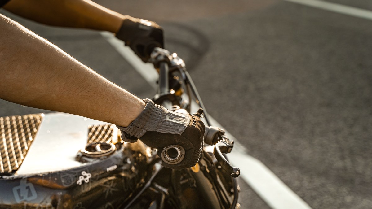 Rider gripping motorcycle handlebars in short-cuff ventilated dual-sport / trail gloves