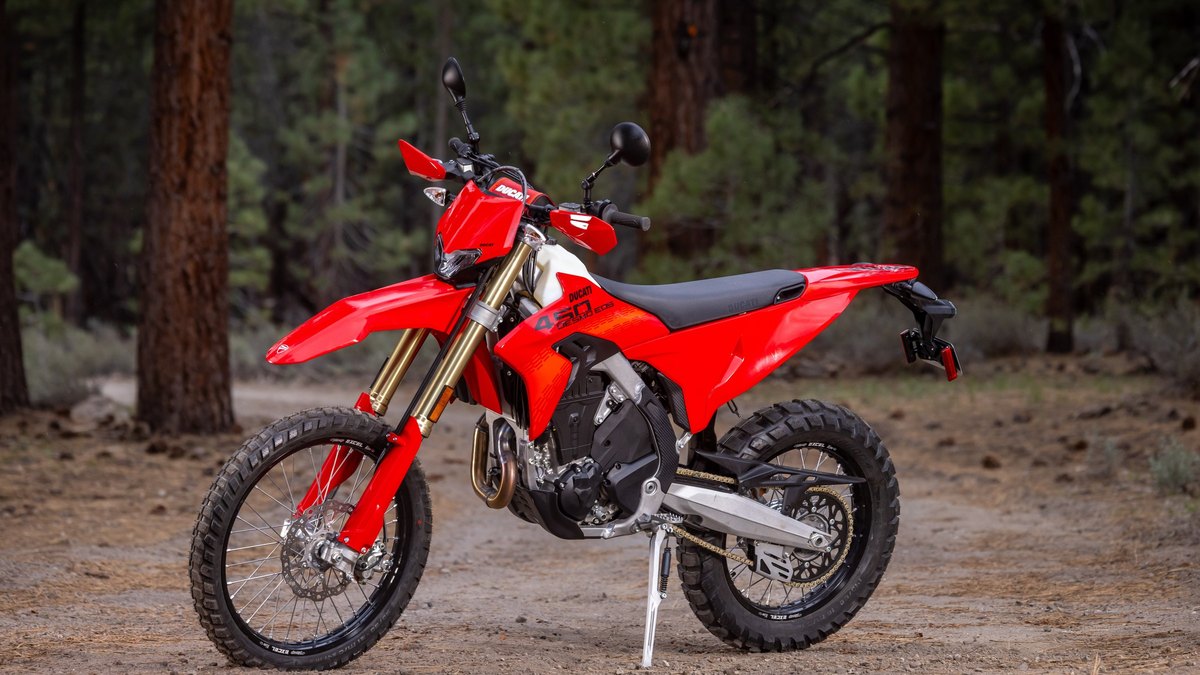 Street-legal Ducati Desmo450 EDS enduro with lights and plate on a forest dirt road